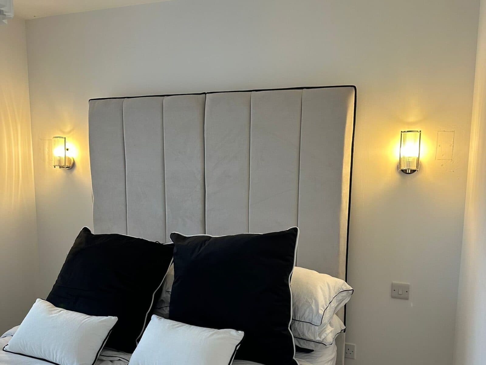 Bedroom with a pair of warm wall lights either side of a tall headboard