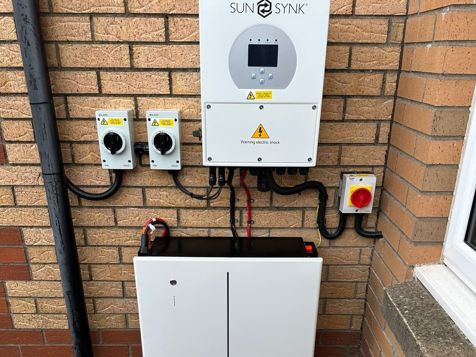 Sunsynk solar inverter, isolators and home battery fitted on a brick wall